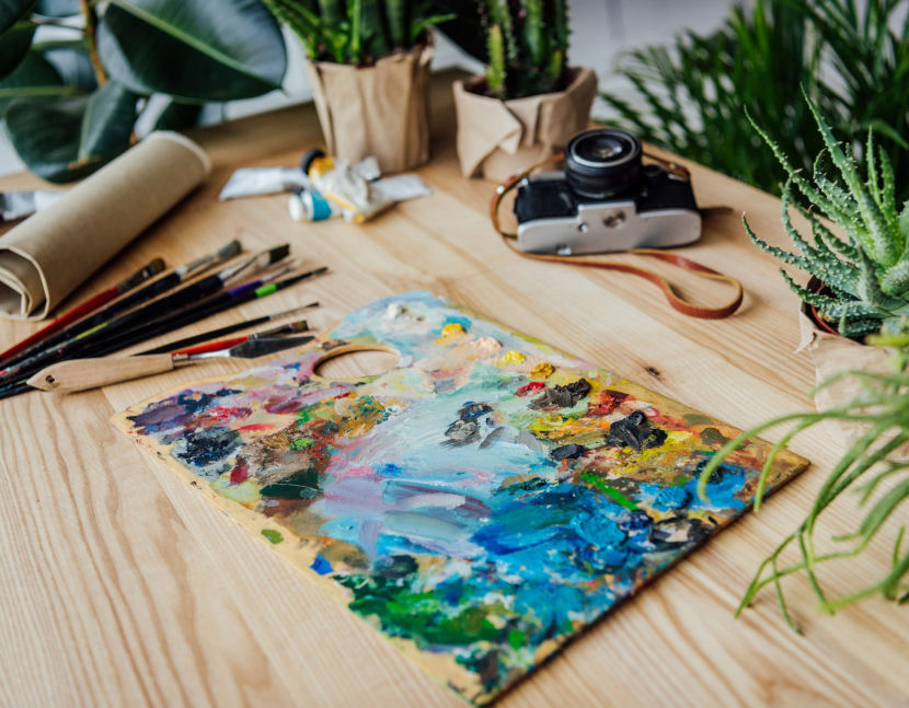 Creative workplace with art supplies, vintage camera and potted succulent plants